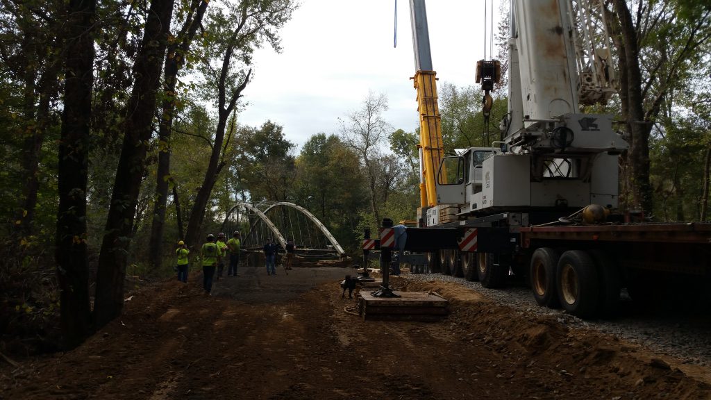 A crane setting a restored truss in place